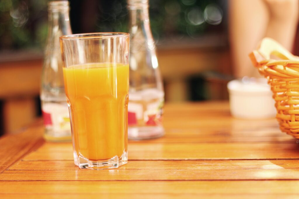 Close-up of a refreshing glass of orange juice on a wooden table, perfect for summer.