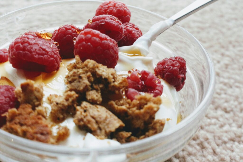 Close-up of a breakfast bowl with yogurt, fresh raspberries, and granola.