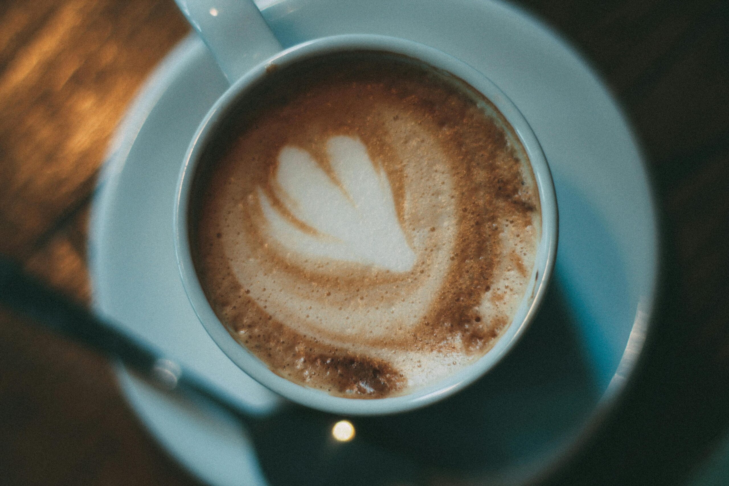 Close-up of a cappuccino with heart latte art on a wooden table in Tallinn cafe.